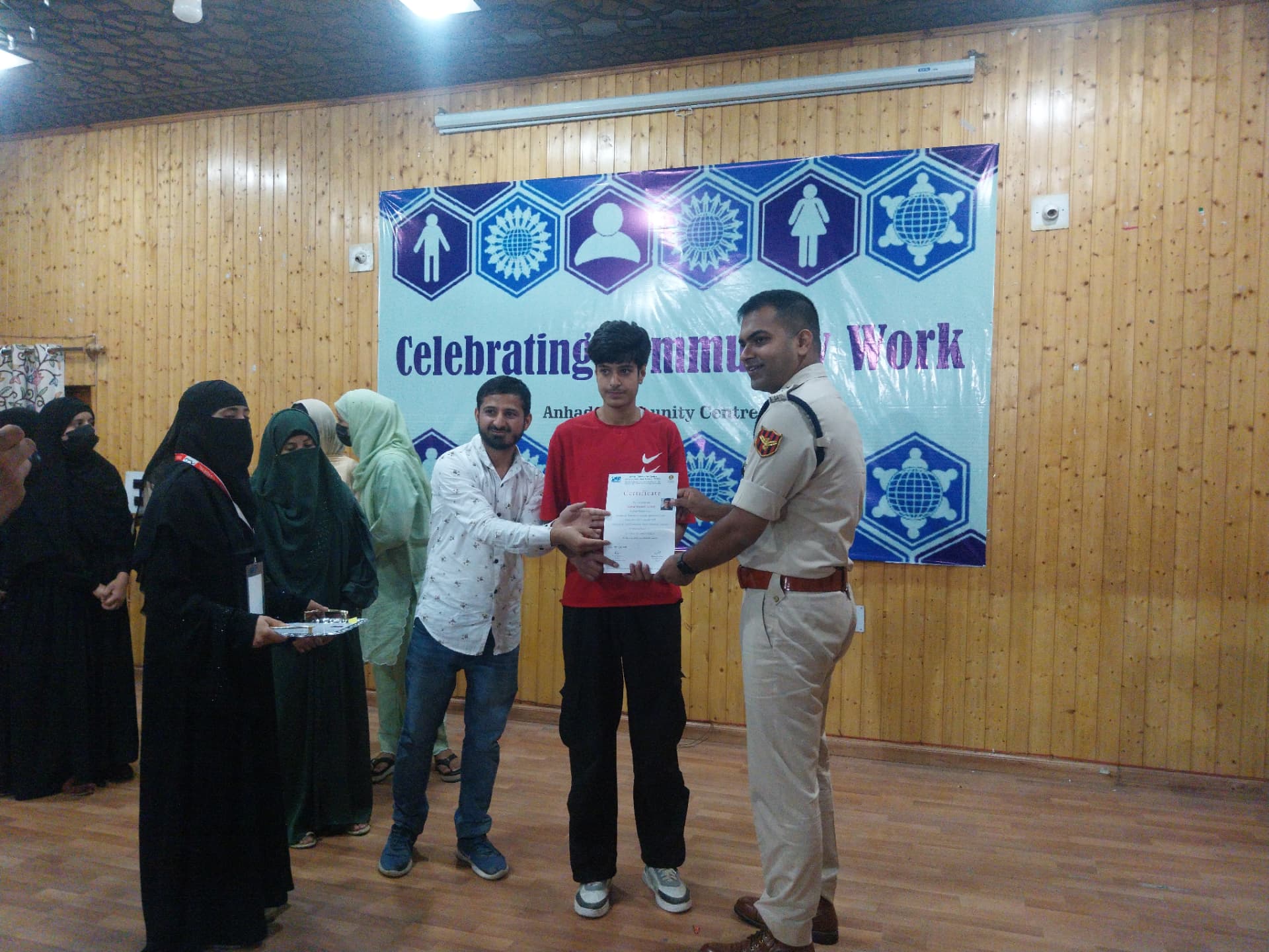 A young participant receiving a certificate at a community work celebration