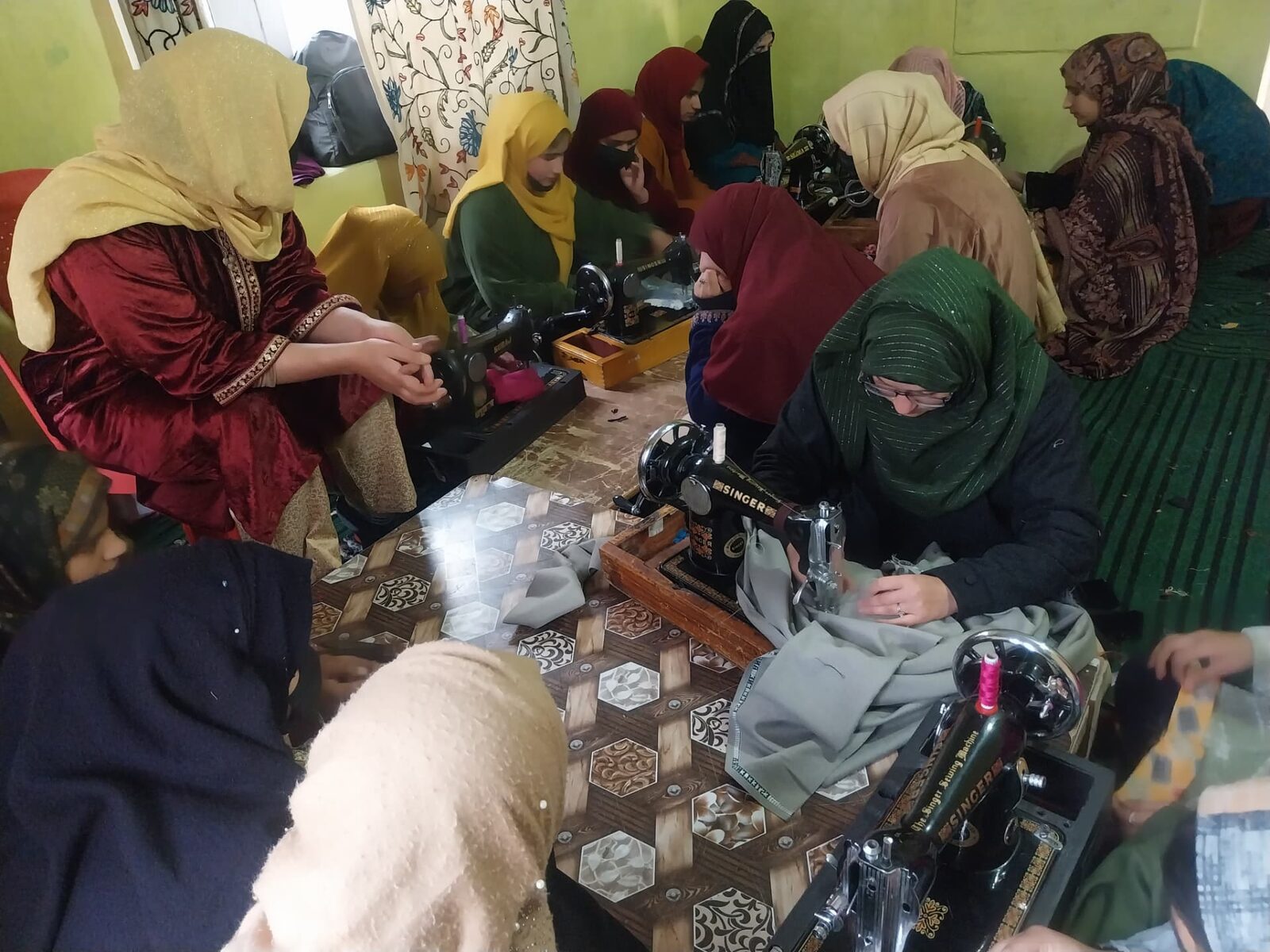 Women learning to stitch on sewing machines at the tailoring centre